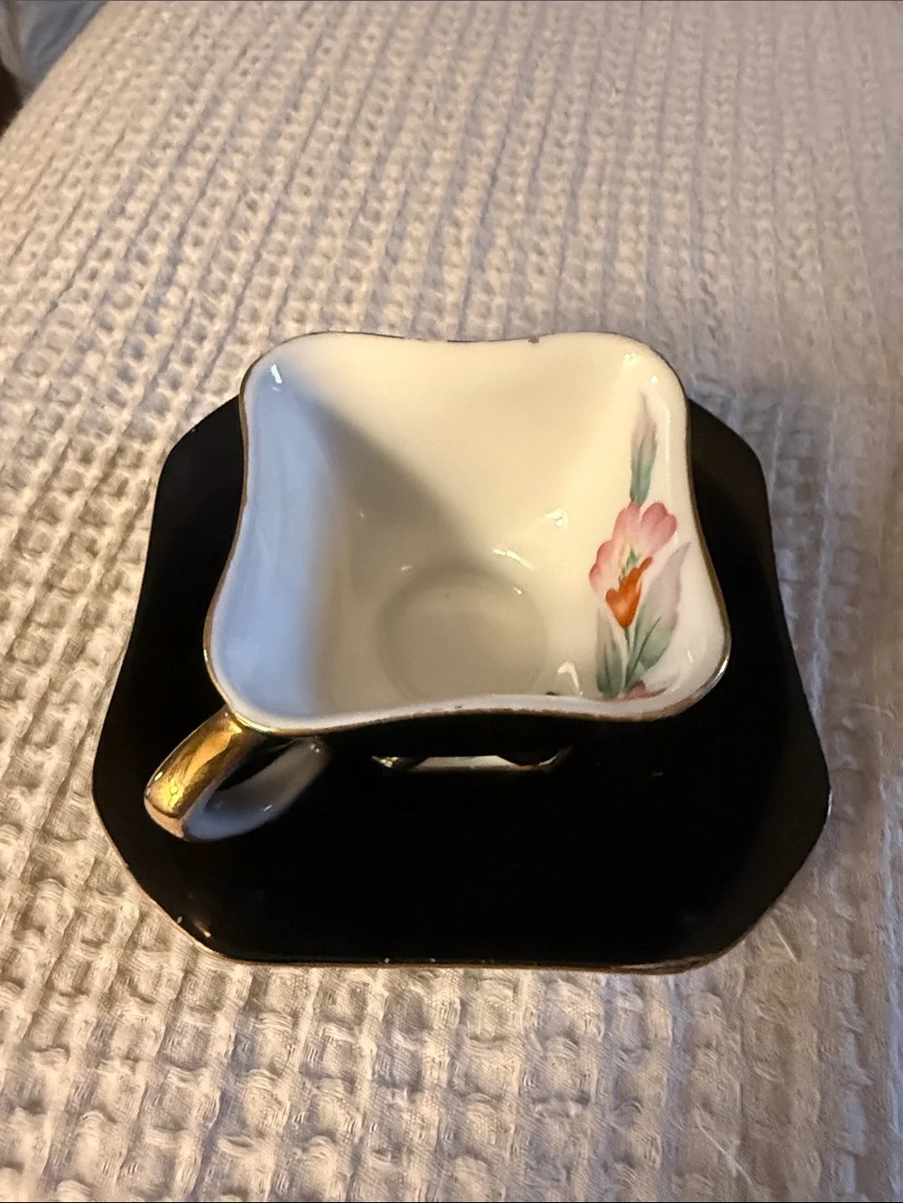 Merit Black and Gold Porcelain Teacup with Floral Accent